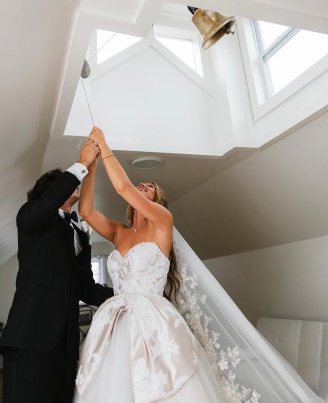 A bride and groom ring the estate bell together beneath the skylight