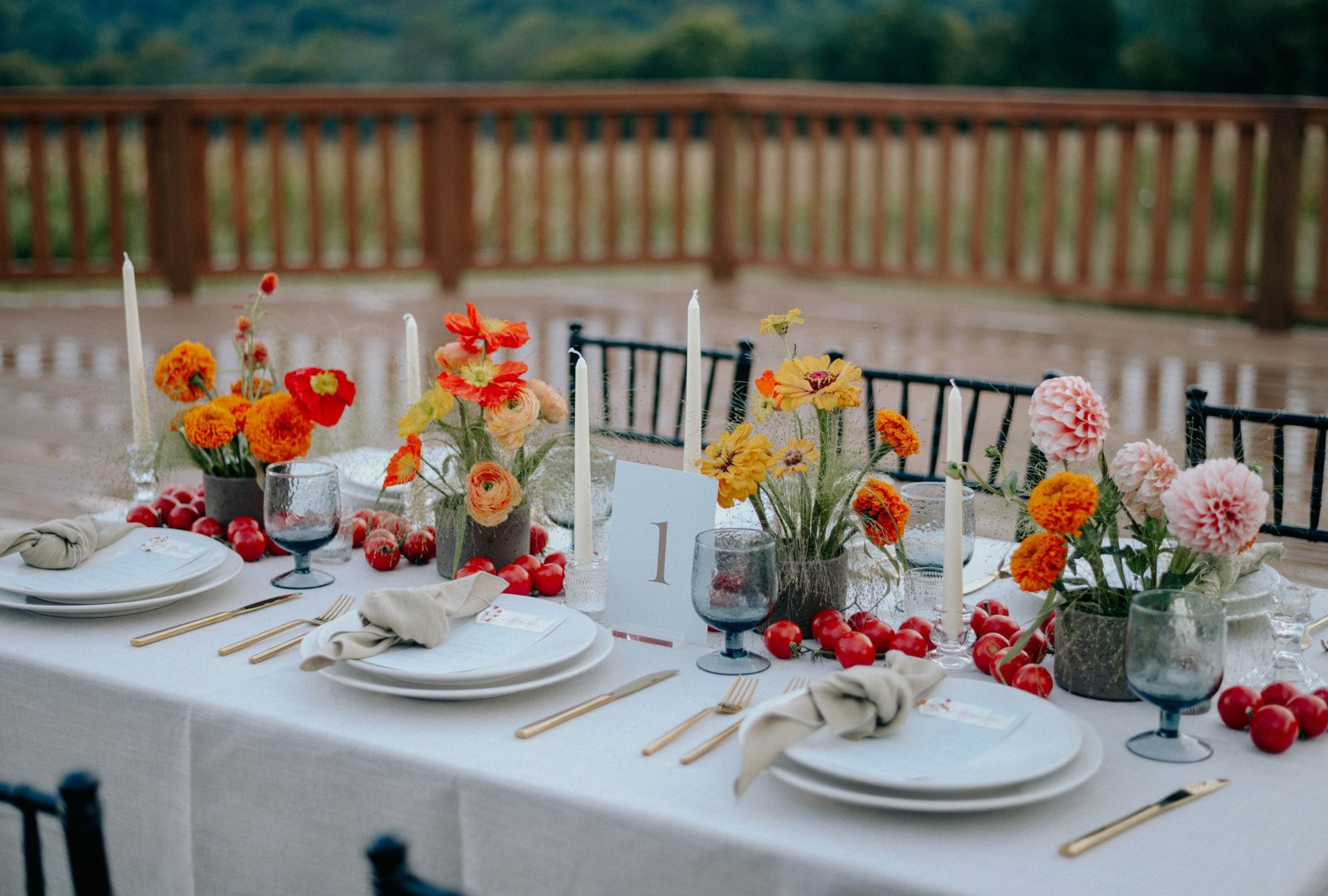 Long tables set for dinner in the pavilion, chargers and glassware down both sides